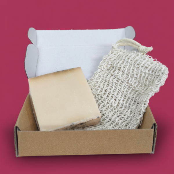 An open cardboard box containing a white sponge and a small block of light-colored soap.
