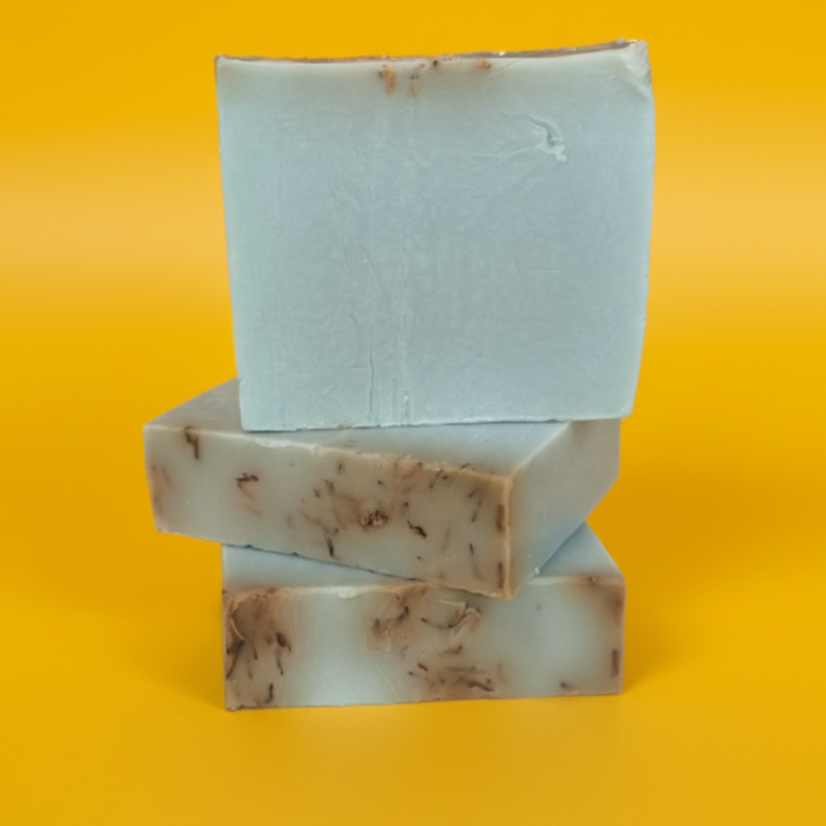 A stack of three rectangular bars of soap against a yellow background.