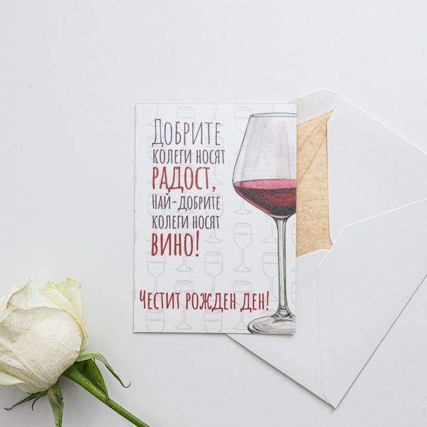 a white rose sitting next to a card with a picture of a glass of wine