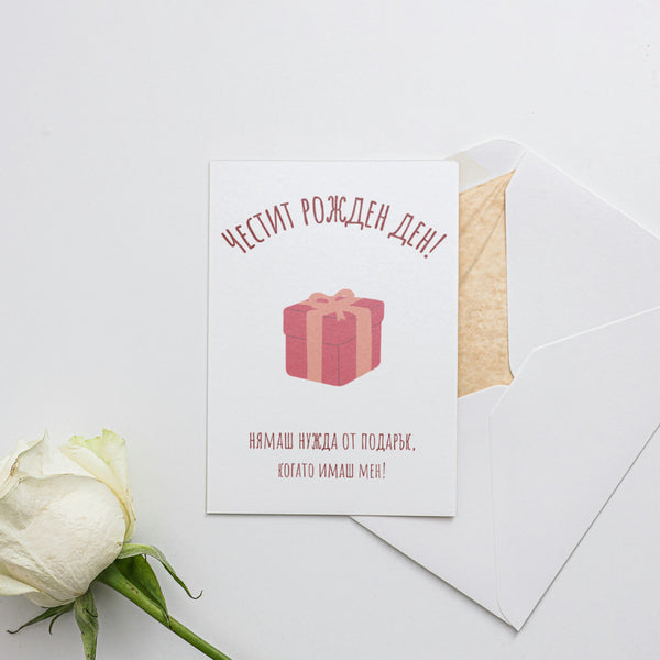 a white rose sitting next to a card with a present on it